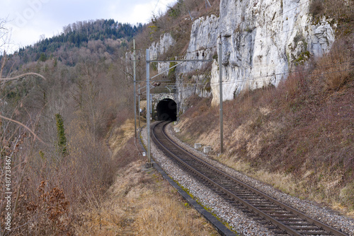 Empty railway tracks with tunnel portal near railway station of St-Ursanne on a cloudy winter day. Photo taken February 7th, 2022, Saint-Ursanne, Switzerland. photo