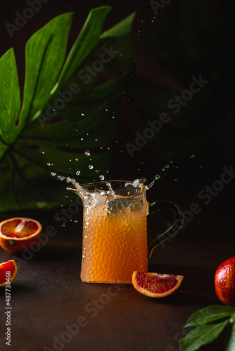 Wallpaper Mural Orange juice splash. Fresh orange juice in a glass decanter and red orange fruit slices on on a dark background. Torontodigital.ca
