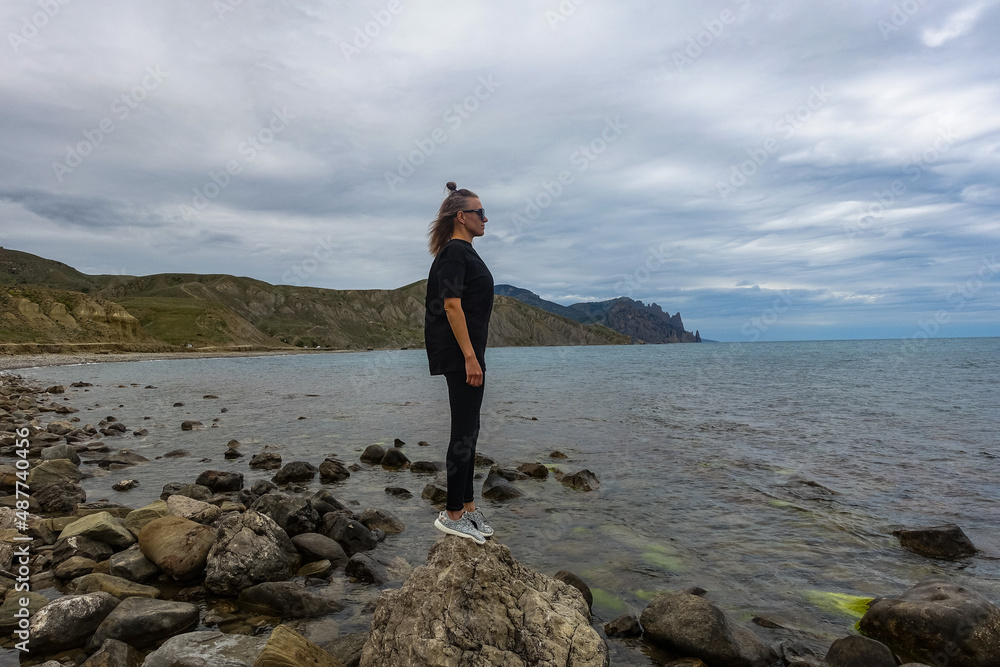 A girl on the shore of the Fox Bay - a bay of the Black Sea near the Kara-Dag mountain range. Crimea.