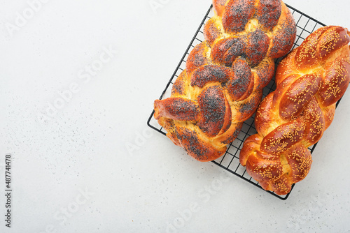 Challah bread. Sabbath kiddush ceremony composition. Freshly traditional baked homemade braided challah bread for Shabbat and Holidays on light grey background, Shabbat Shalom. Top view. Copy space. photo