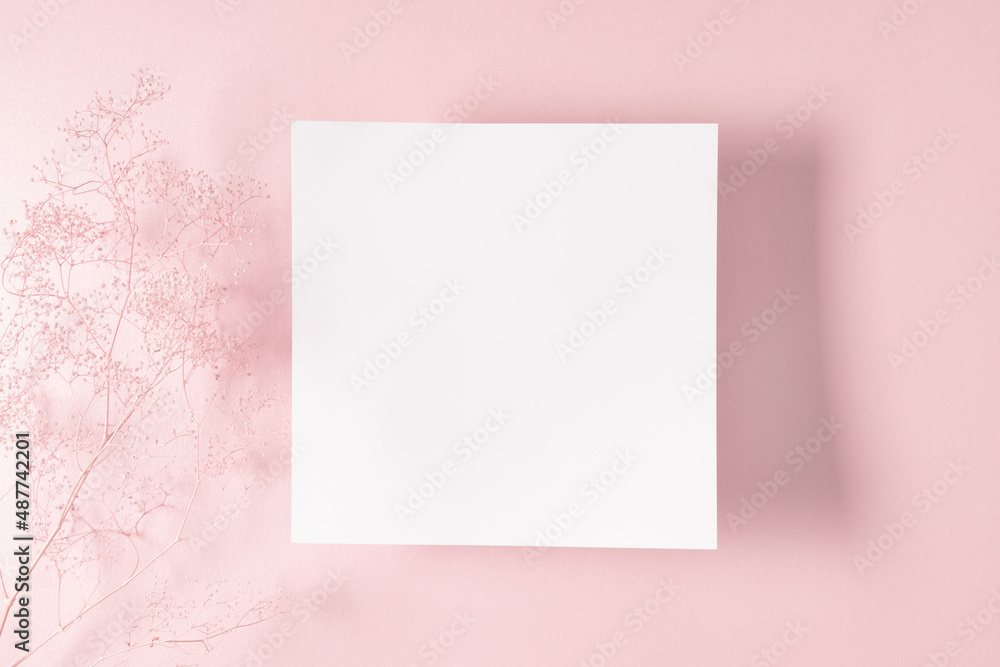 White paper empty blank, dry flowers, dried twig on pink background. Invitation card mockup on beige table. Flat lay, top view, copy space, mockup White paper empty blank, dry flowers, dried twig on pink background. Invitation card mockup on beige table. Flat lay, top view, copy space, mockup
