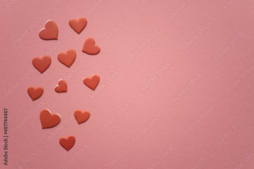 Red hearts on pink paper table. Copy space.