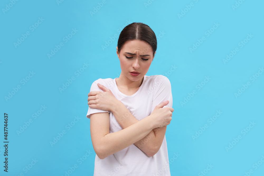 Woman suffering from fever on light blue background. Cold symptoms Woman suffering from fever on light blue background. Cold symptoms