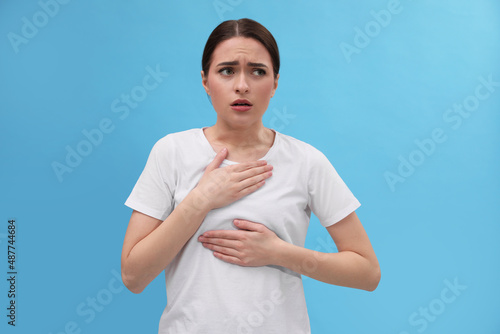 Woman suffering from cold on light blue background photo