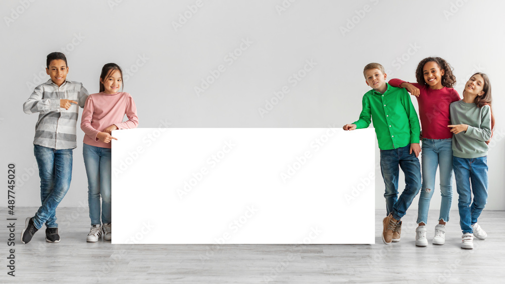 Happy Diverse Kids Standing Near White Board Over Gray Background Happy Diverse Kids Standing Near White Board Over Gray Background
