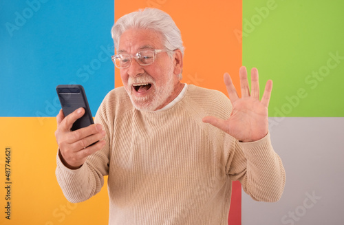Portrait of adult senior man with shocked facial expression looking at mobile phone. 70 years old grandfather wearing eyeglasses overjoyed surprised reading message with good news, winner, success © luciano