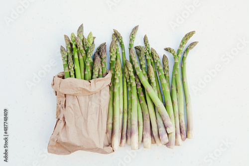 Organic green freshly cut asparagus stalks packed in eco-package on white background. Copy space, top view, horizontal image.  Asparagus officinalis. Spring healthy cooking idea concept photo