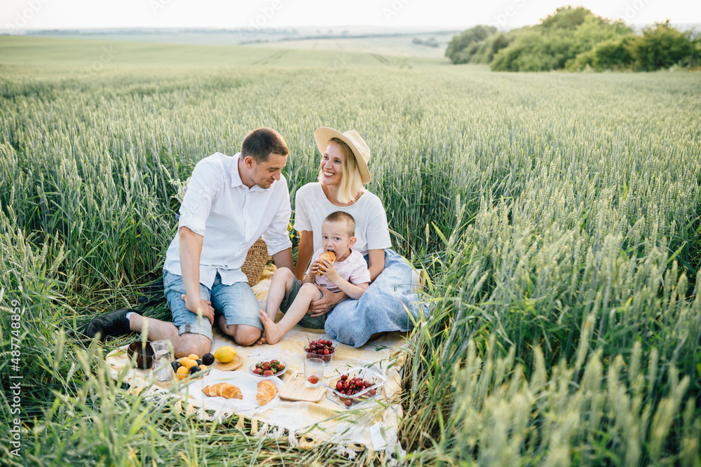 Happy family with little son relaxing in a picnic in a wheat field. Happy family with little son relaxing in a picnic in a wheat field.