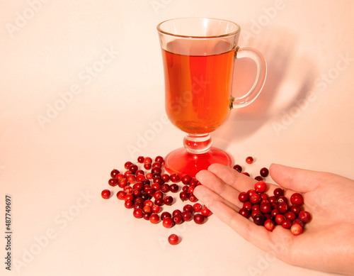 cranberry tea in a glass and cranberries in hand