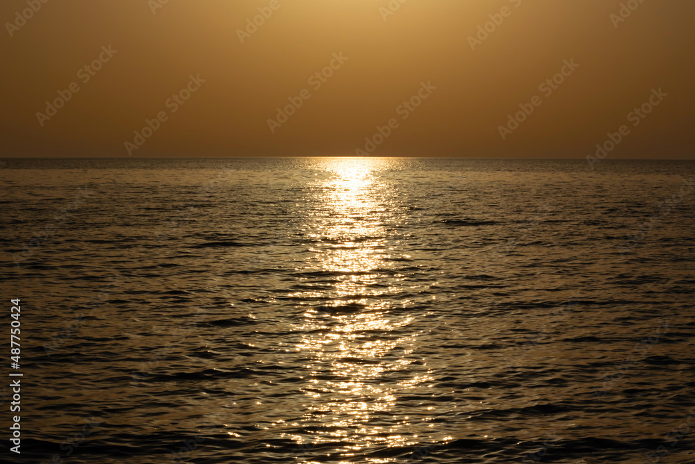 Orange sunset on the sea with a path from the light of the sun. Soft selective focus. Nature beauty, travel concept