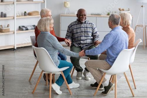 Multiracial group of happy pensioneers sitting in circle, holding hands