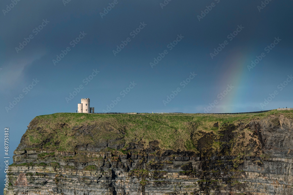 O'Brien's Tower and colorful rainbow in blue sky. Cliff of Moher, Ireland. Famous travel destination. Irish luck concept.