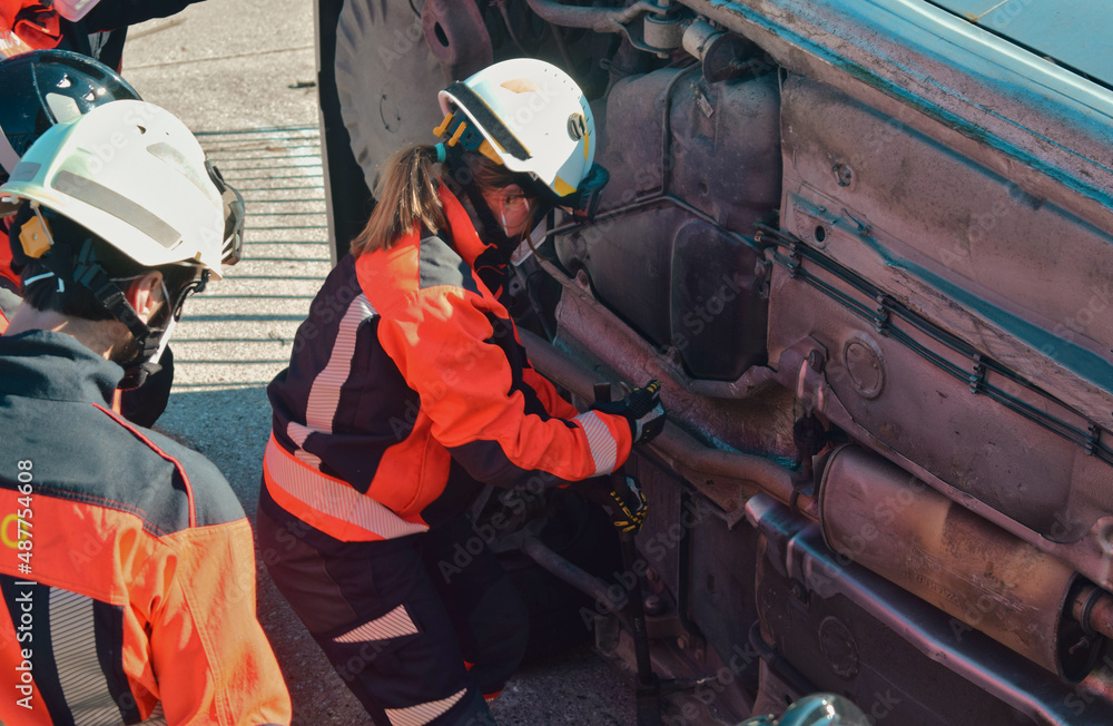 Fototapeta premium Female firefighter in front of a crashed car trying to rescue a victim