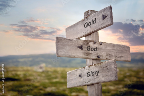 gold god glory text quote on wooden signpost outdoors in nature during sunset.