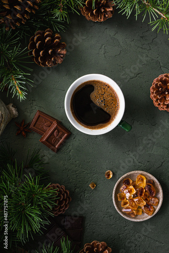 Wallpaper Mural Black coffee in a green cup, chocolate and caramel sugar on a green background with fir branches and cones. Top view Torontodigital.ca