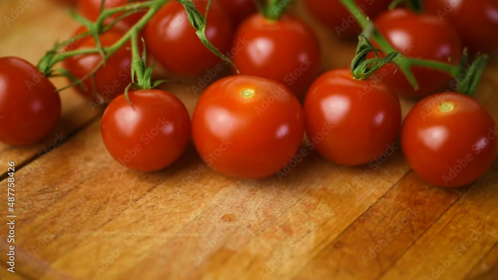 Cherry tomatoes on a branch are spinning on a cutting board. Cherry tomatoes on a branch are spinning on a cutting board.