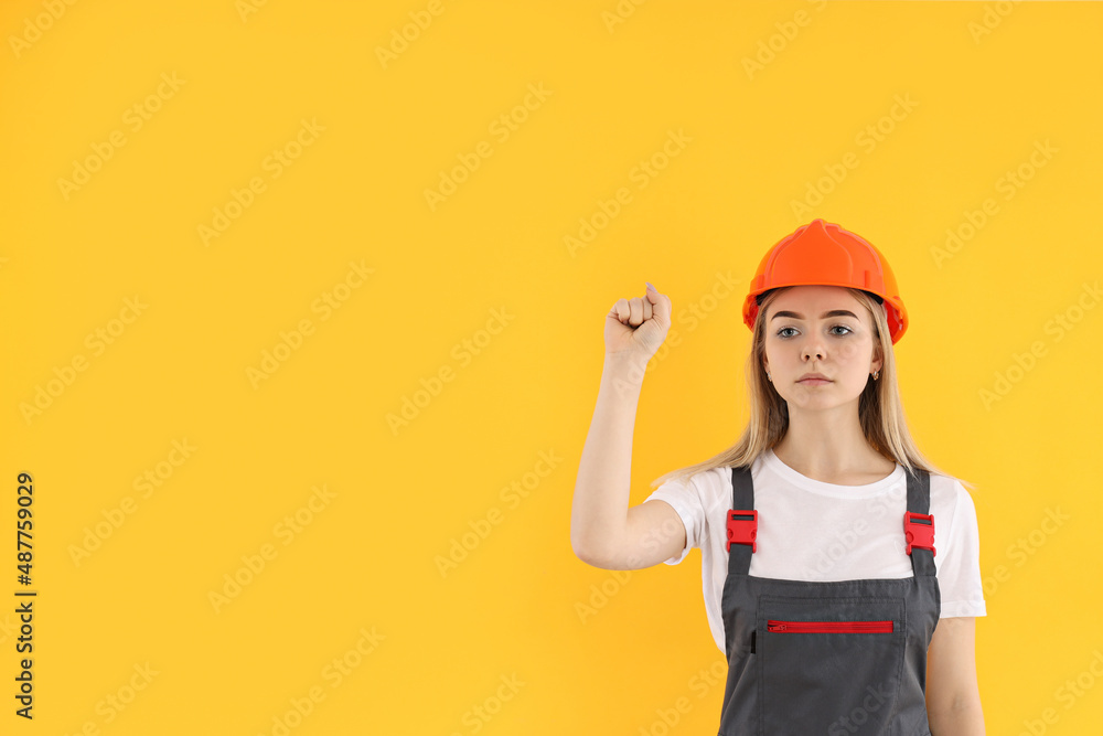 Girl power concept with female builder on yellow background