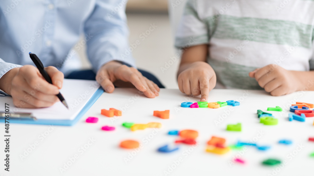 Private child lessons. Little boy counting colorful numbers, studying with professional woman therapist at office Private child lessons. Little boy counting colorful numbers, studying with professional woman therapist at office
