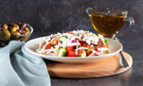 Shopska salad on dark background background and wooden board with gray textiles