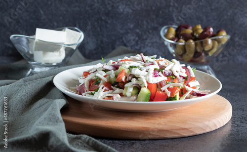 Shopska salad on wooden board, dark background background with gray textiles