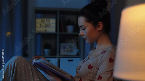 education, school and people concept - teenage student girl reading book in bed at home at night