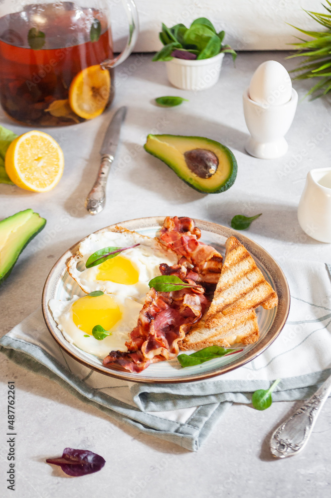 A dish with scrambled eggs and bacon for breakfast in bright sunlight