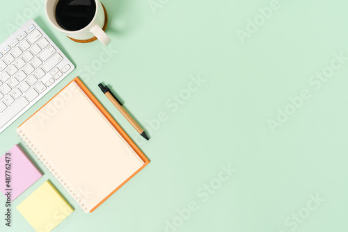 Creative flat lay photo of workspace desk. Top view office desk with keyboard and open mockup black notebook on pastel green color background. Top view mock up with copy space photography.