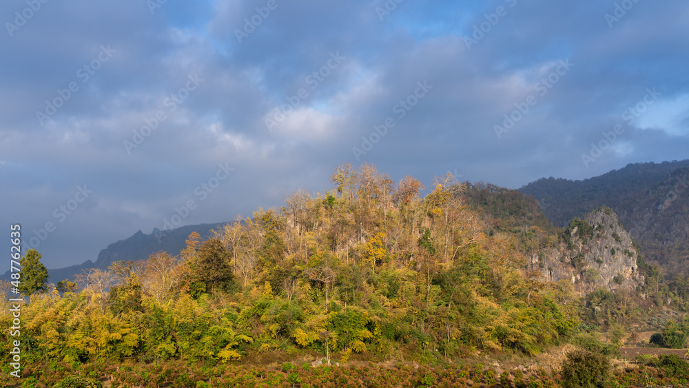 Scenic hill and mountain landscape with fall colors in early morning sunlight in beautiful rural valley, Chiang Dao, Chiang Mai, Thailand