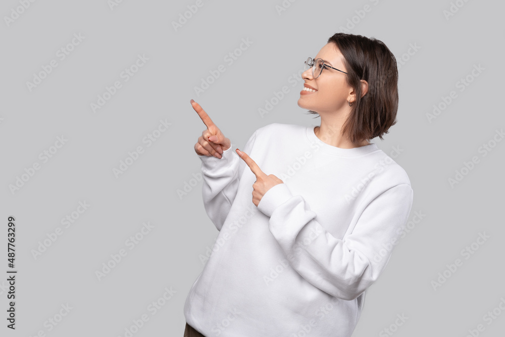 Charming young woman is pointing up with fingers at empty background. Charming young woman is pointing up with fingers at empty background.