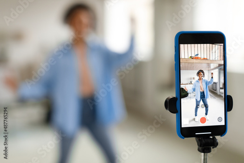 Cheerful black woman filming video on cell phone