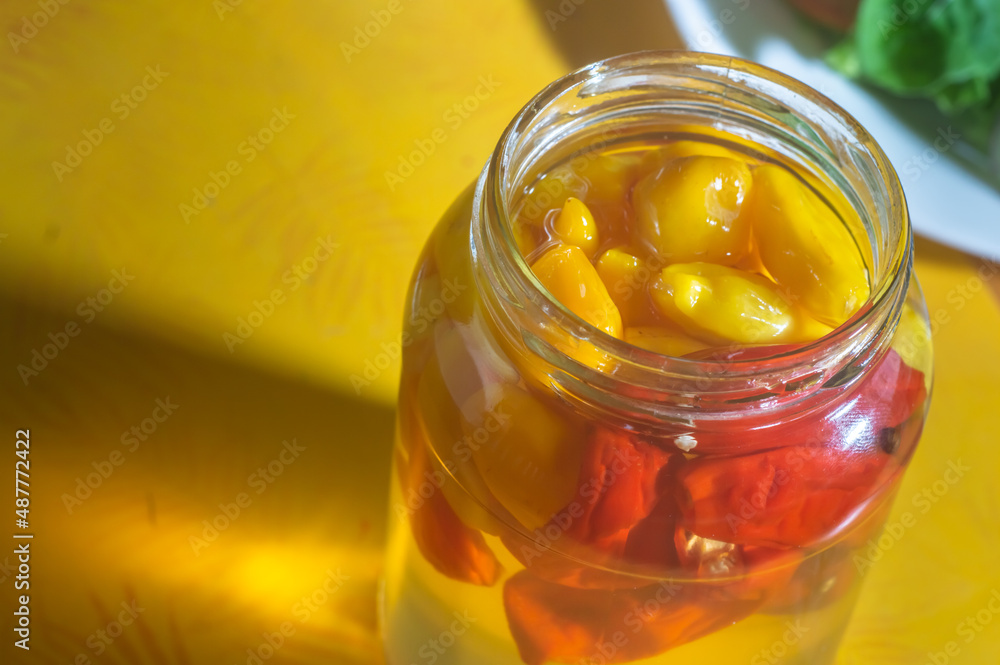 Canned yellow peppers in a jar on wooden background,natural light Canned yellow peppers in a jar on wooden background,natural light