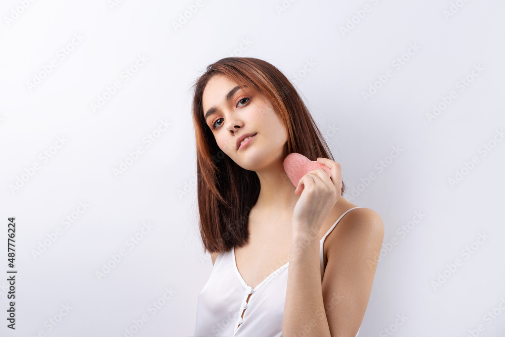 Beautiful smiling woman with clean skin, natural make-up and white teeth on a gray background. Holding a pink hygienic heart. Beautiful smiling woman with clean skin, natural make-up and white teeth on a gray background. Holding a pink hygienic heart.