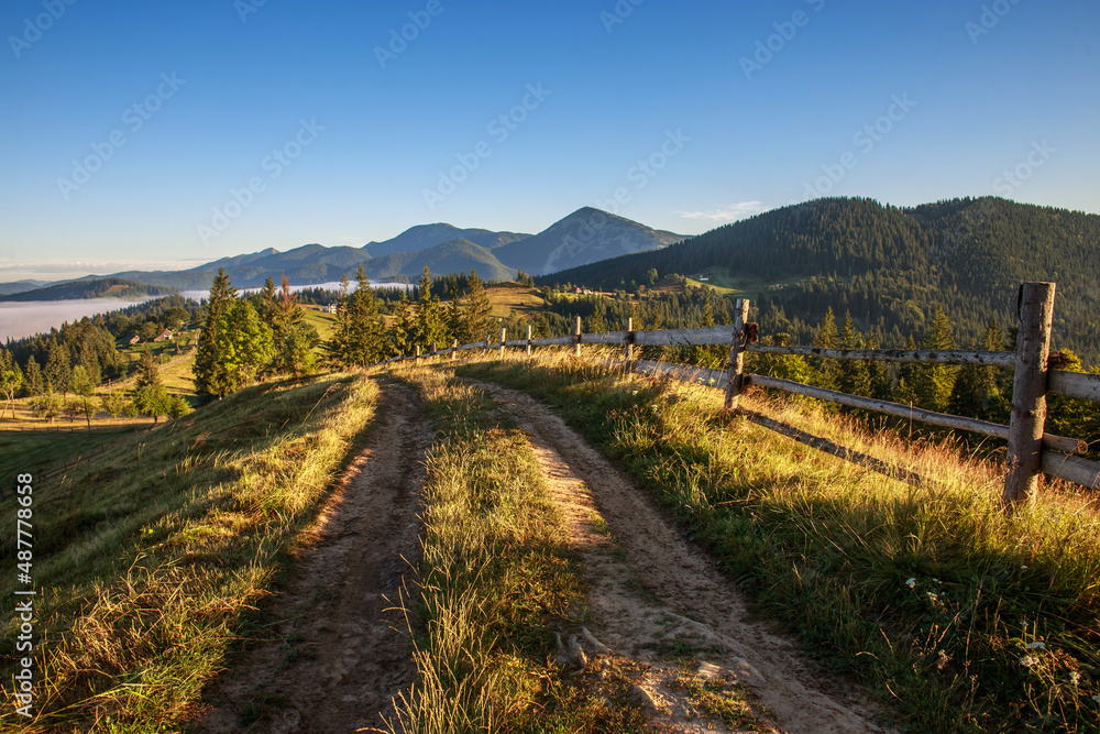 Road is high in mountains, fields, forests and farmland on background of blue sky, Carpathians, Ukraine Road is high in mountains, fields, forests and farmland on background of blue sky, Carpathians, Ukraine