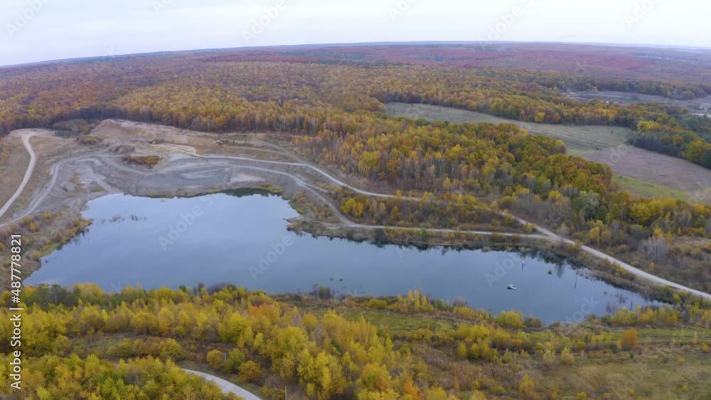 A large clay pit for the production of bricks, with a clean lake in the middle of a beautiful autumn forest in Ukraine. Aerial photo drone copter photo from a bird's eye view. A large clay pit for the production of bricks, with a clean lake in the middle of a beautiful autumn forest in Ukraine. Aerial photo drone copter photo from a bird's eye view.