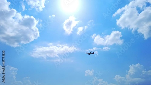 Flying airplane in the cloudy blue sky. Cloudscape sky with copy space. Airplane taking off over mountains and sea. Travel by air transport