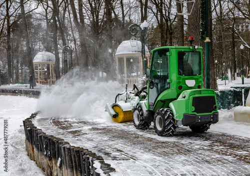 Snowplow on snow removal in the park puffs of snow from under a working machine photo