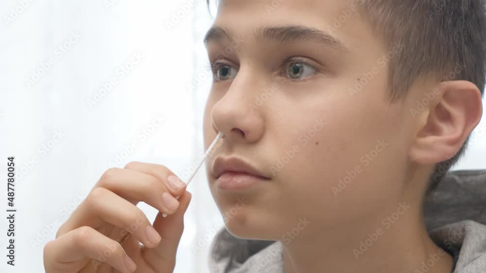 Teenage boy taking antigen self-test for Covid-19 with rapid diagnostic test kit. Kid using nasal swab while doing coronavirus test at home before go to school lessons Teenage boy taking antigen self-test for Covid-19 with rapid diagnostic test kit. Kid using nasal swab while doing coronavirus test at home before go to school lessons