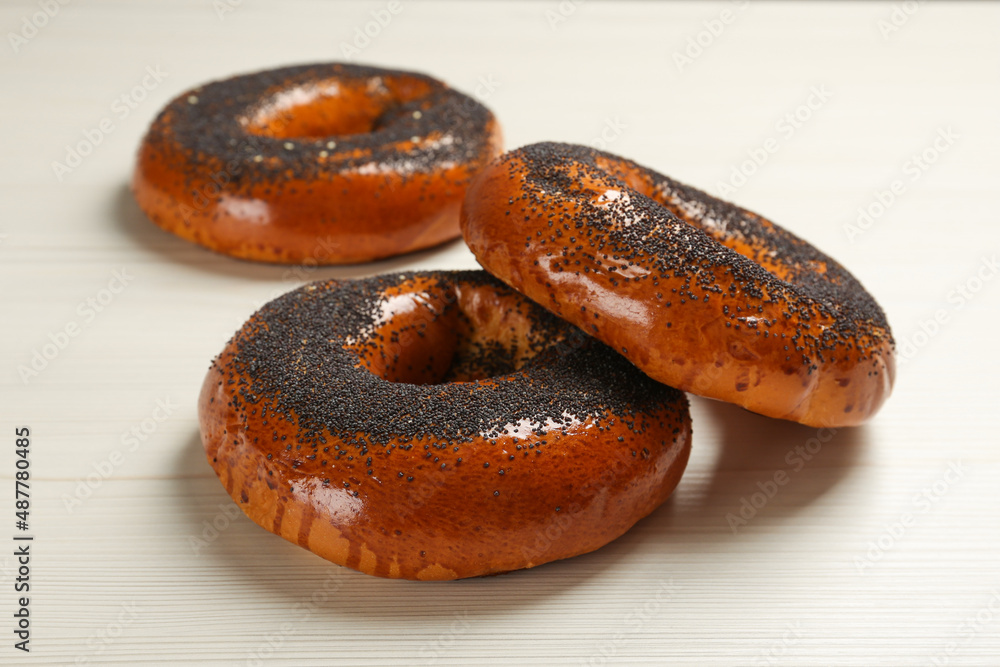 Delicious fresh bagels with poppy seeds on white wooden table Delicious fresh bagels with poppy seeds on white wooden table