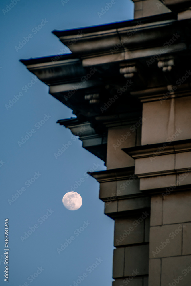 Full moon during the day on dusk next to a building roof. Beautiful wallpaper landscape. High quality photo