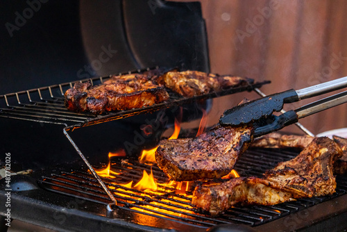 gas grill with grilled meat and grill tongs