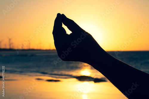 Silhouette of a man's hand performing yoga on the beach