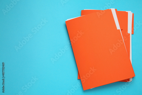 Orange files with documents on turquoise background, top view. Space for text