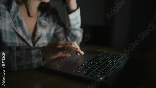 Woman browsing internet in front of laptop screen at night