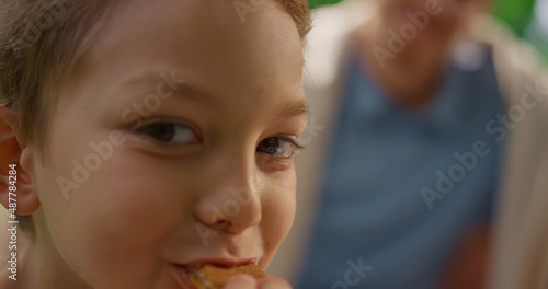 Cute boy eating coockies looking on camera close up. Portrait of munching child.