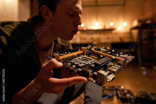Man blowing dust from motherboard for mining