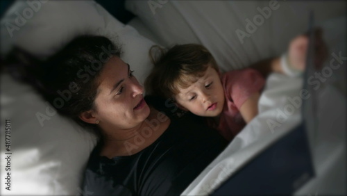 Mother telling bedtime story to toddler mom holding book night routine photo