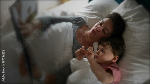 Fotografie Mother lying in bed with child reading a bedtime story before sleep