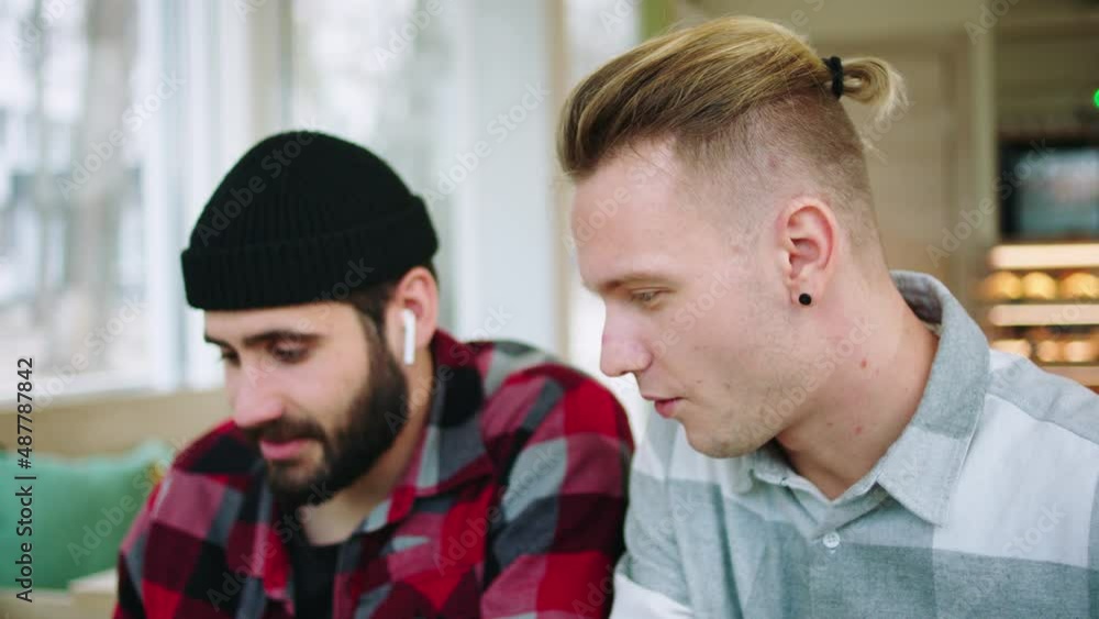 At the modern coffee shop two charismatic guys with a large smile using the laptop to watch something they enjoy the moment laughing. 4k At the modern coffee shop two charismatic guys with a large smile using the laptop to watch something they enjoy the moment laughing. 4k