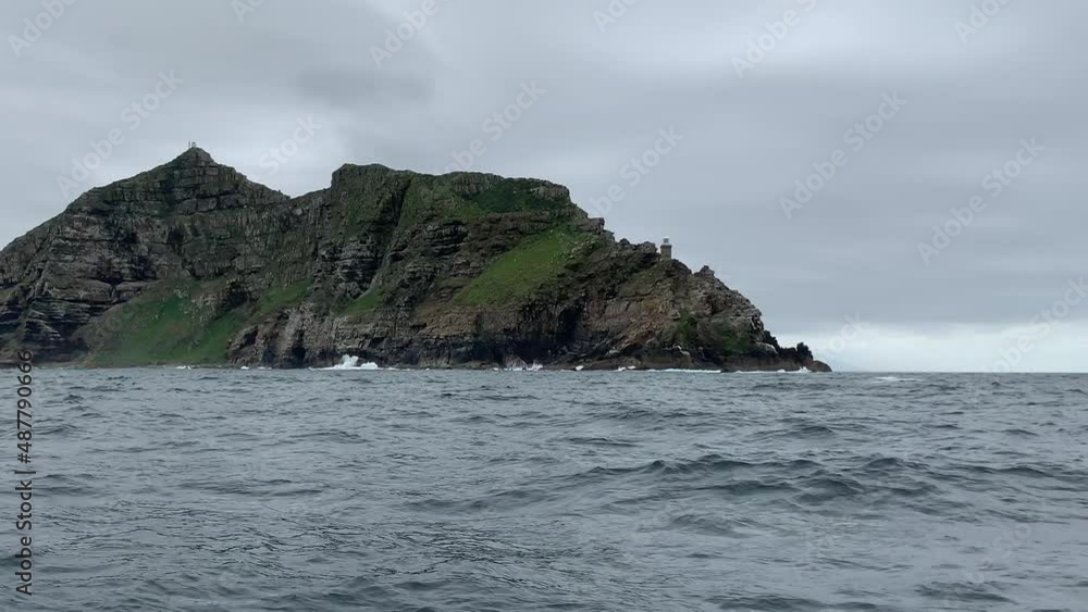 Cape Point at the Southern tip of Africa as seen from a sailboat at sea. Waves crashing on rocks. Cape Point at the Southern tip of Africa as seen from a sailboat at sea. Waves crashing on rocks.