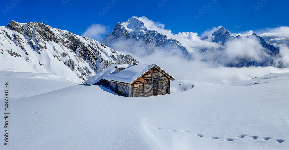 Verschneite Hütte vor den Schweizer Bergen